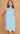 Woman wearing a light blue dress with floral details on a beige background