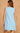Light blue sleeveless dress with lace details on a beige background