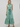 A sleeveless, multicolor vertically striped maxi dress with a tie waist and ruffled hem, modeled on a plain light gray studio background.