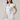 Woman wearing a white dress with floral patterns on a plain background