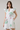 Woman wearing a white dress with floral patterns on a plain background
