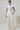 Woman wearing a blue floral blouse and beige pants against a plain background