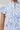 White blouse with blue floral and bird pattern on a gray background