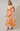 Woman wearing a floral dress with orange and pink pattern on a plain background