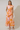 Woman wearing a floral dress with orange and pink pattern on a plain background