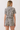 A woman shown from the back wearing a short-sleeve collared romper with a zebra print pattern in black and off-white, against a plain light background.