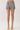 A model from the waist down wearing high-waisted shorts with a black and white zebra print, paired with beige heeled sandals, against a plain light background.