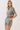 A woman modeling a matching short-sleeve cropped button-front shirt and high-waisted shorts set in a black and beige zebra print, photographed against a plain light background.