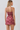 A woman shown from the back wearing a two-piece matching set consisting of a spaghetti-strap crop top and a high-waisted mini skirt, both in a dusty rose and pink paisley pattern against a light gray studio background.