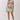 A woman modeling a sleeveless bodycon mini dress with an impressionistic painting print, standing against a plain light gray studio background.