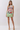 A woman modeling a sleeveless bodycon mini dress with an impressionistic painting print, standing against a plain light gray studio background.