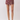 A model's lower body wearing a pair of high-waisted, short wrap-style shorts with a maroon and gold paisley pattern, paired with beige heeled sandals against a light gray studio background.