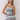 A woman modeling a sleeveless mini dress with a retro horizontal stripe pattern in brown, light blue, cream, and white, set against a plain light gray studio background.