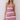 A woman modeling a sleeveless, scoop-neck mini dress with horizontal pink, magenta, and burgundy stripes against a plain light gray studio background.