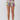 A model's lower body wearing high-waisted, ruffled shorts with a colorful floral and butterfly print on a light beige background, photographed against a neutral light gray studio backdrop.