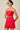 Woman wearing a strapless red dress with a beige background