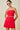 Woman wearing a red strapless dress with a beige background