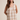 Woman wearing a beige and white checkered sleeveless top and shorts on a beige background