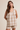 Woman wearing a beige and white checkered sleeveless top and shorts on a beige background