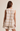 Woman wearing a beige and white checkered top and shorts on a beige background
