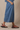 Person wearing a blue denim skirt with black sandals on a beige background