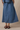 Person wearing a blue denim skirt on a beige background
