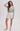 A woman modeling a gray and white striped long-sleeve top, white shorts, and white Mary Jane flats against a light gray studio background.