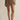 Person wearing a brown skirt on a beige background