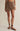 Person wearing a brown skirt on a beige background