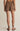 Person wearing brown shorts on a beige background