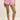 Person wearing pink pajama shorts with lace trim on a beige background