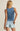 Person wearing a blue tank top and denim shorts on a beige background