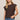 Woman wearing a brown top with unique shoulder designs against a beige background