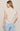 Woman wearing a beige top with button details on a plain background