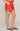 Person wearing a red skirt with white embroidery on a plain background