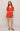 Woman wearing a red embroidered outfit on a plain background