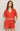 Woman wearing a red embroidered outfit on a plain background
