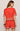 Woman wearing a red outfit with white patterns on a plain background