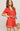 Woman wearing a red embroidered outfit on a plain background