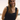 Woman wearing a black sleeveless top with a scenic background