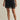 Black lace-trimmed skirt worn by a person on a beige background