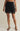 Black lace-trimmed skirt worn by a person on a beige background