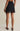 Black skirt with lace details worn by a person on a beige background