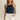 Woman wearing a navy sleeveless top with white trim and a white denim skirt on a beige background