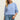 Woman wearing a light blue sweater and jeans against a plain background