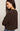 Woman wearing a brown sweater against a plain background