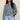 Woman wearing a teal sweater and light blue jeans against a beige background