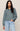 Woman wearing a teal sweater and light blue jeans against a beige background