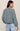 Person wearing a light blue sweater and jeans on a beige background