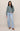 Woman wearing a green sweater and light blue jeans on a beige background